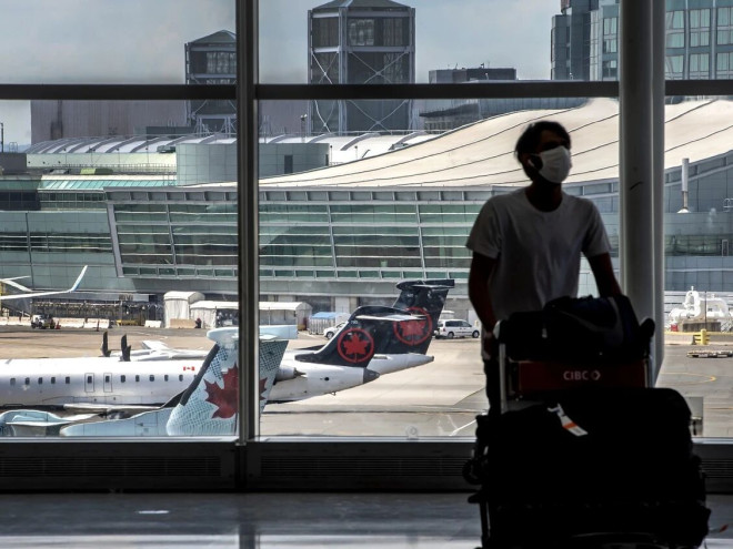 一名旅客在机场推着行李车，窗外可见跑道